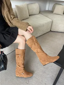 Vista detallada de botas altas de ante marrón con cuña, ideales para un estilo otoñal elegante.