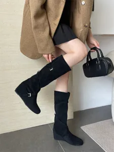 Detalle de botas altas de antelina negra con cuña, tiras con hebilla y tacón oculto muy cómodo.