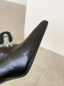 Primer plano detallado de la bota de cuero negro con punta puntiaguda y costuras finas.