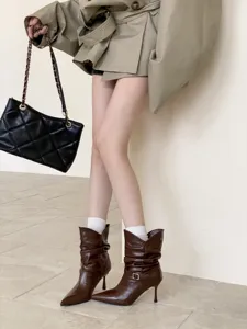 Vista detallada de botas slouchy retro con punta y tacón de aguja, elegante diseño de cuero marrón.