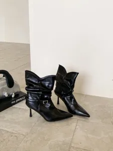 Botines negros de punta con tacón de aguja y hebilla, elegante estilo otoñal chic.
