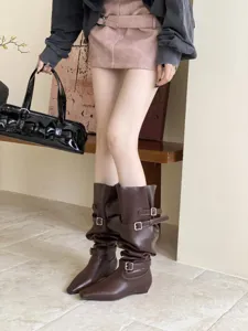 Detailed shot of stylish dark brown slouchy boots featuring metallic buckles and low block heels.