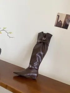 Detailed view of women's dark brown knee high boots with low heel and stylish buckle design.