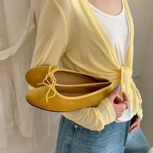 Yellow velvet ballet flats detail featuring delicate bow tie and comfortable flat sole design.