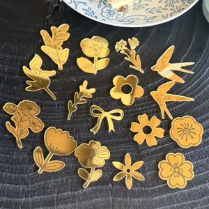 Vista dettagliata di topper per cupcake in acrilico specchiato dorato, fiori e uccelli.
