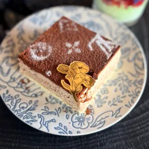 Primo piano dettaglio di torta dolce di lusso con topper di fiori in acrilico dorato.