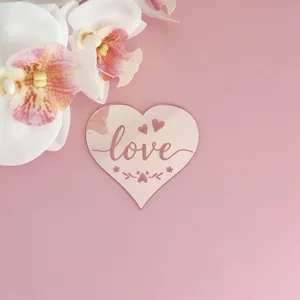 Détail de cake topper en acrylique en forme de cœur avec gravure love et belle décoration.