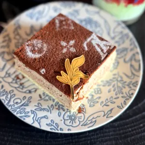 Primo piano dettagliato di una torta quadrata con topper in acrilico dorato su piatto.