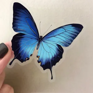 Close up detail of transparent PET blue butterfly sticker for DIY journal notebook decor.