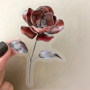 Close up view of a transparent floral sticker with silver metallic outline and copper red petals.