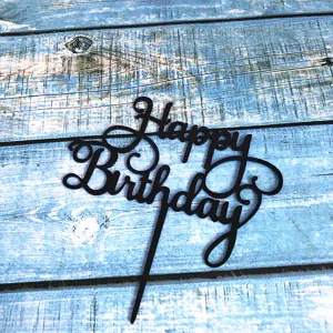 Detail shot of black acrylic Happy Birthday cake topper, elegant cursive party decor.