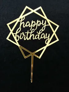 Detalle de primer plano del adorno de tarta de feliz cumpleaños acrílico dorado con marco geométrico.