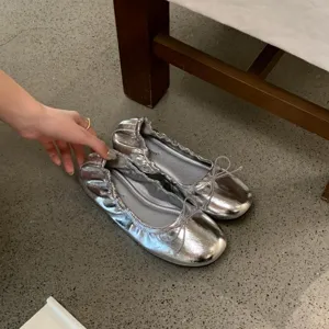 Close-up van zilveren metallics platte ballerinas met subtiel strikdetail, elegante damesschoen.