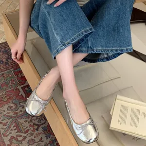 Gedetailleerde close-up van zilveren platte balletschoenen met een schattige strik.