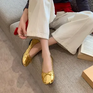 Mooie detailopname van gouden platte ballerina's met een ronde neus en chique strik.