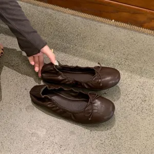 Gedetailleerd overzicht van bruine platte ballerina's voor dames met ronde neus en strik.