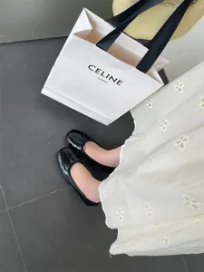 Detail view of black patent leather flat ballet shoes, elegant bow detail, minimalist chic.