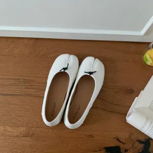 White split-toe flat ballet shoes detail shot, minimalist slip-on design with cute bow knot.