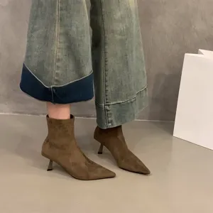 Detail view of brown suede pointed toe high heel ankle boots showcasing texture and design.