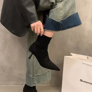 Close-up detail shot of black pointed toe high heel sock boots with slim heel and stylish upper design.