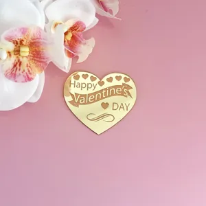 Détail de décoration de gâteau en cœur doré avec texte Happy Valentines Day et fleurs.