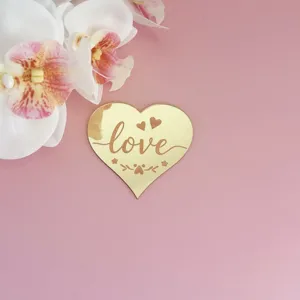 Gros plan détaillé d'un joli cake topper miroir en cœur doré brillant avec le texte love