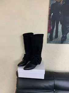 Detailed view of black pointed-toe mid-calf boots, featuring suede and leather detail.
