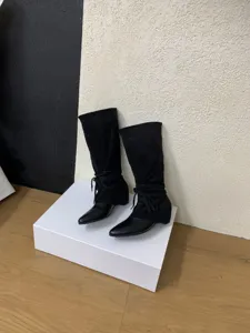 Detail shot of black pointed toe western cowboy mid-calf slouchy boots with stylish tie design.