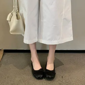 Gedetailleerd shot van zwarte platte schoenen met ronde neus en strikdecoratie.
