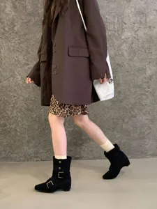 Vue détaillée de bottes mi-mollet en suédine noire avec boucles métalliques et talons épais.