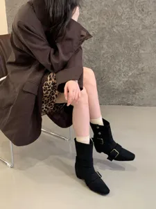 Bottes mi-mollet en daim dotees de boucles metalliques, bout carre et talon carre epais.