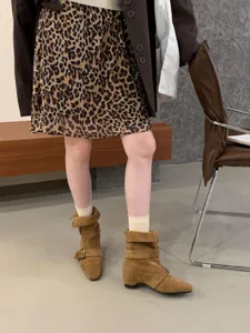 Détail de bottes mi-mollet en daim marron, style vintage et texture douce pour la saison.