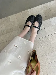 Dettaglio ballerine Mary Jane intrecciate nere, design traforato con fibbia sui gradini.