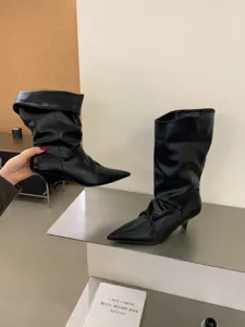 Vista detallada de botas negras de punta con tacón de aguja, cuero prémium, estilo francés chic.