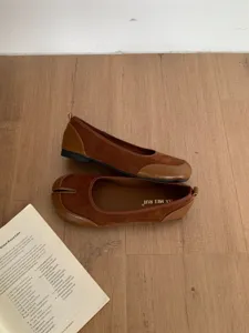 Scatto dettagliato di scarpe basse Mary Jane marroni con punta divisa su pavimento.