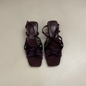 Detail view of purple square toe strappy heeled sandals, showing cross straps and elegant design.
