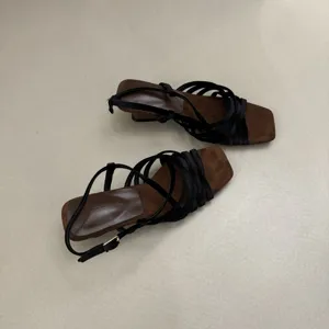 Detailed view of women's square toe strappy low heel sandals in chic brown and black.