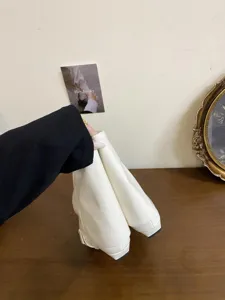 Dettaglio di stivaletti bianchi con punta quadrata e tacco basso, stile francese elegante e chic.