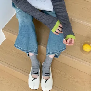 Detailed shot of split-toe flat ballet shoes paired with grey socks on wooden stairs.