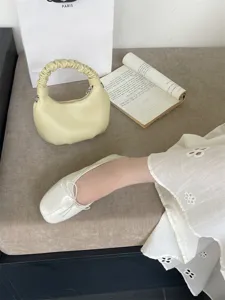Detail shot of elegant women's flat ballet shoes with delicate bow knot in soft white.