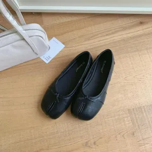 Detail view of black split toe flat ballet shoes, featuring minimalist design and soft leather.