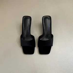 Detail shot of black velvet square toe high-heeled mules, elegant and modern women's footwear.