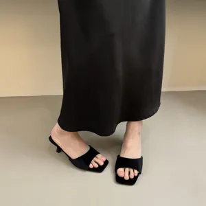 Close-up of black velvet square-toe kitten heel slide sandals, showing sleek texture.