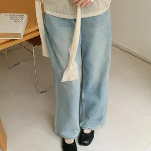 Detail shot of split-toe flat shoes paired with blue wide-leg jeans and knit top.