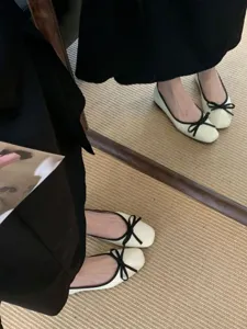 Detailed view of French square toe flat ballet shoes with black bow, soft sole scene shot.