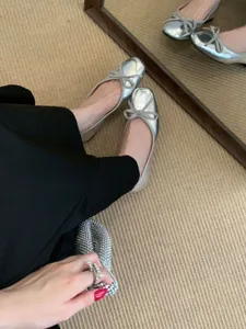 Detail shot of silver metallic square-toe ballet flats with bow, showcasing soft sole and design.