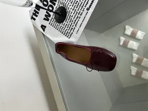 Close-up detail shot of burgundy retro flat ballet shoes with a square toe and delicate bow tie.