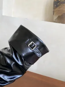 Vista detallada de botas largas brillantes negras para mujer con elegante hebilla de metal.