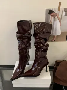 Elegantes botas altas vintage de charol para mujer con tacón de aguja y punta afilada.