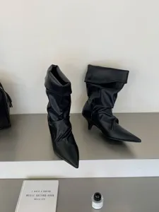 Vista detallada de elegantes botines negros con tacón alto y punta fina estilo chic.